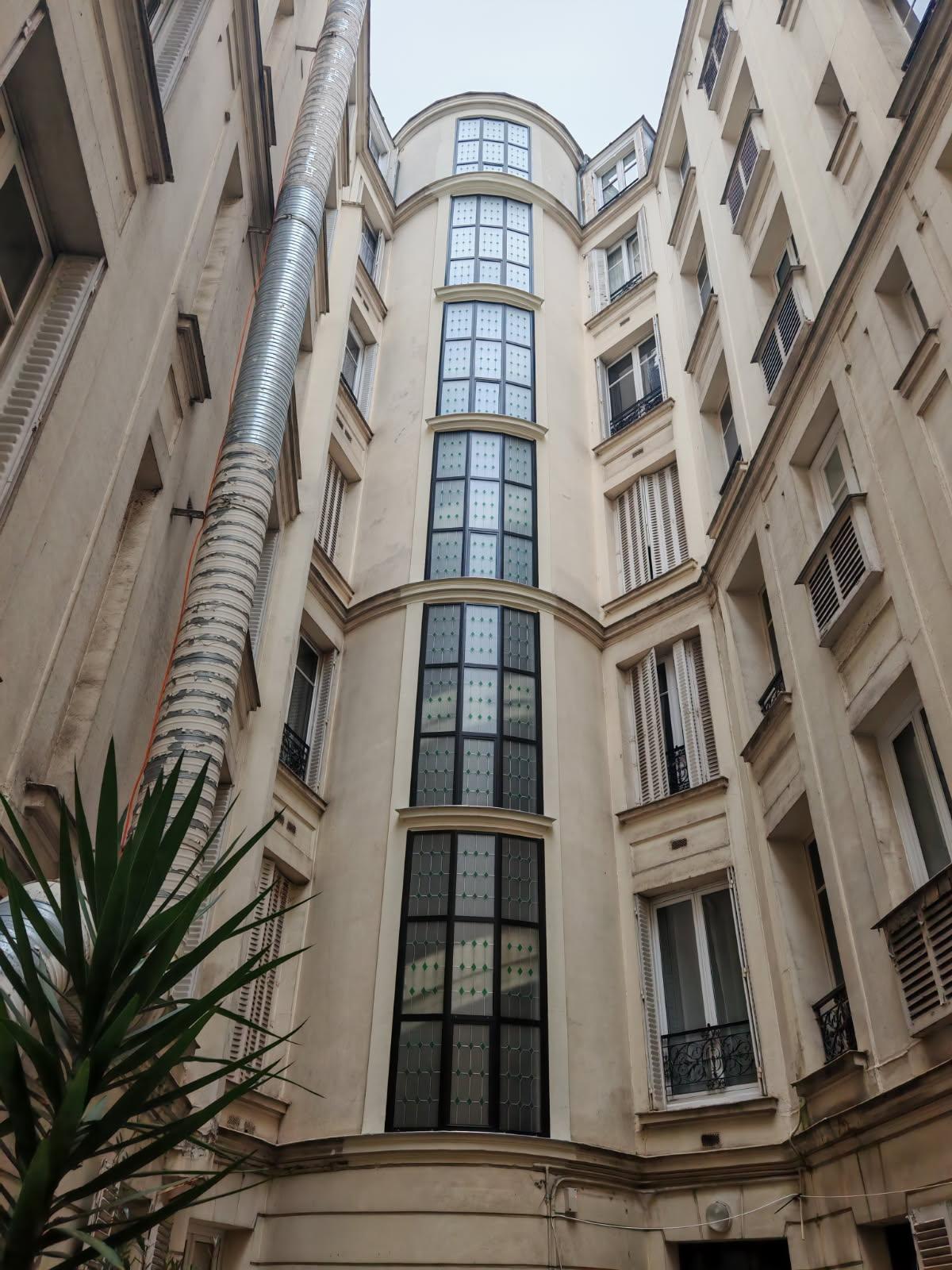 Ensemble vitré cintré en acier, sur la cage d’escalier d’un bâtiment patrimonial